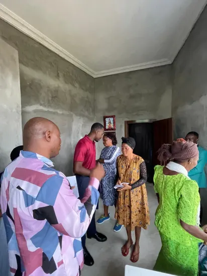 Pastor Joseph Ante presenting an envelope of support to a widow, Nigeria 2026