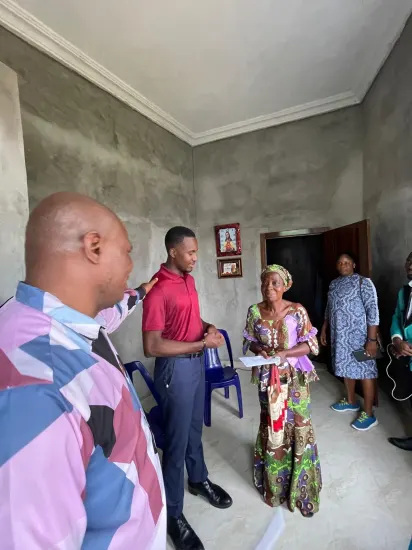 Pastor Joseph Ante presenting an envelope of support to a widow, Nigeria 2026