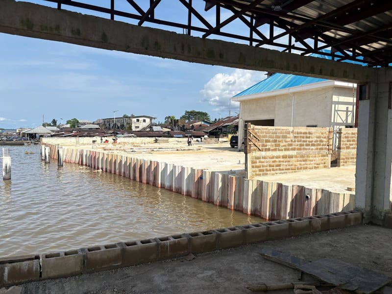 A new retaining wall along the river, seen through an unfinished opening in the building